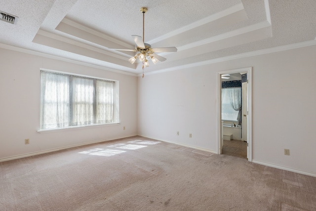 carpeted empty room with a tray ceiling, crown molding, ceiling fan, and a textured ceiling