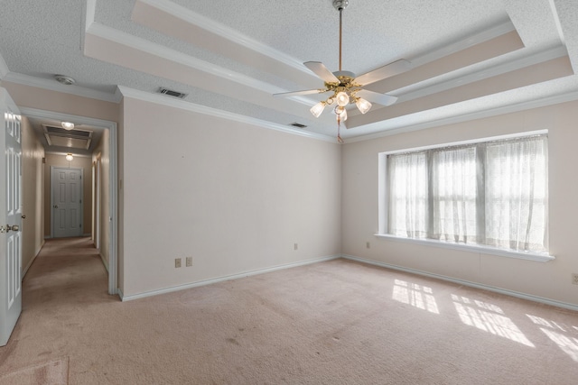 carpeted spare room featuring ceiling fan, a raised ceiling, crown molding, and a textured ceiling