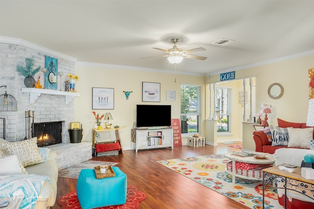 living room featuring crown molding, ceiling fan, a brick fireplace, and dark hardwood / wood-style flooring