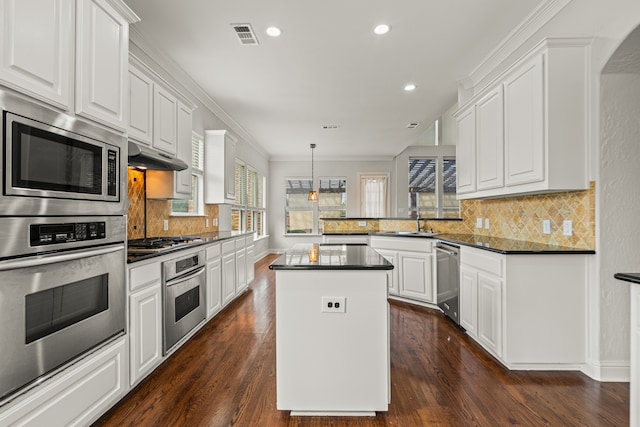 kitchen with a kitchen island, sink, dark hardwood / wood-style floors, appliances with stainless steel finishes, and white cabinets