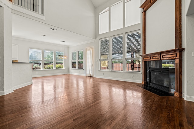 unfurnished living room featuring wood-type flooring and ornamental molding