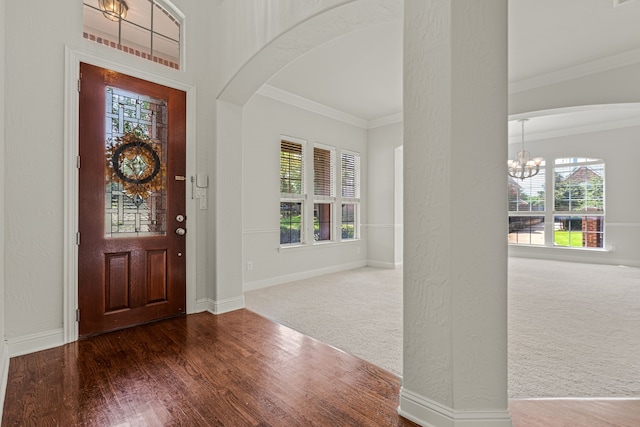 carpeted entryway featuring plenty of natural light, a chandelier, and crown molding