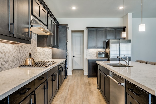 kitchen with sink, hanging light fixtures, light wood-type flooring, tasteful backsplash, and stainless steel appliances