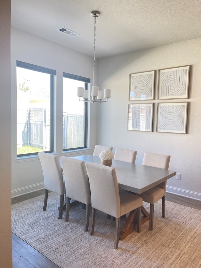 dining area featuring a chandelier, wood-type flooring, and a textured ceiling