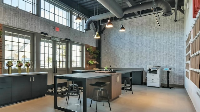 kitchen with french doors, a high ceiling, pendant lighting, a breakfast bar area, and a kitchen island