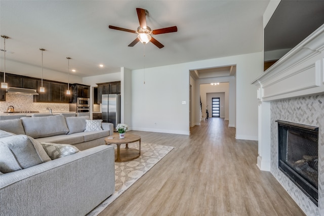 living room featuring a fireplace, light hardwood / wood-style flooring, and ceiling fan