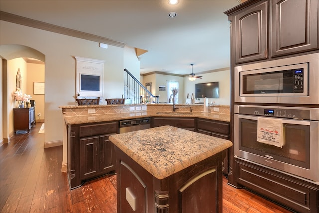 kitchen with dark brown cabinets, sink, stainless steel appliances, and a kitchen island