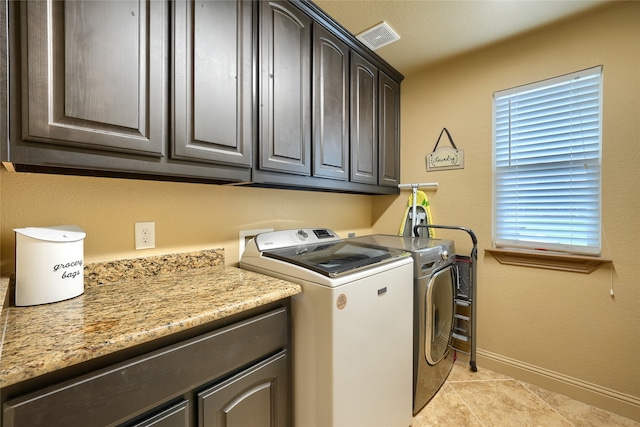 laundry room with cabinets, light tile patterned floors, and washing machine and dryer