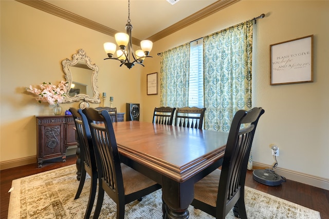 dining area with dark wood-type flooring, crown molding, and a notable chandelier