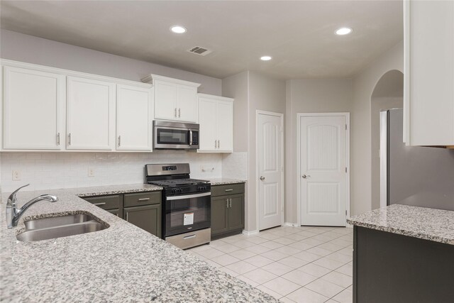 kitchen with light stone countertops, appliances with stainless steel finishes, sink, white cabinetry, and light tile patterned flooring