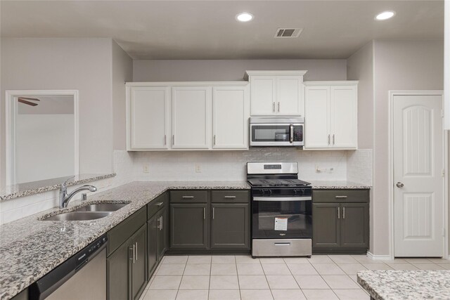 kitchen featuring light tile patterned floors, appliances with stainless steel finishes, sink, light stone counters, and white cabinets