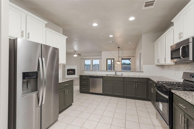 kitchen featuring light stone countertops, stainless steel appliances, sink, ceiling fan, and white cabinets