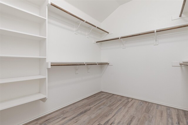 walk in closet featuring light wood-type flooring and lofted ceiling