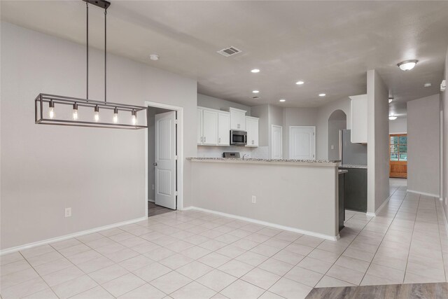 kitchen with kitchen peninsula, light stone countertops, hanging light fixtures, appliances with stainless steel finishes, and white cabinets