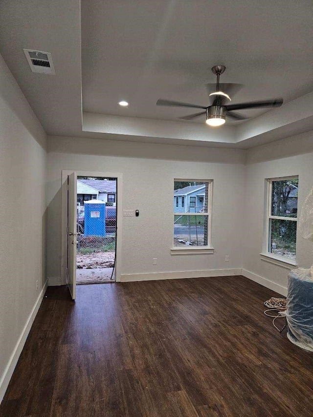 unfurnished living room with a raised ceiling, plenty of natural light, and ceiling fan