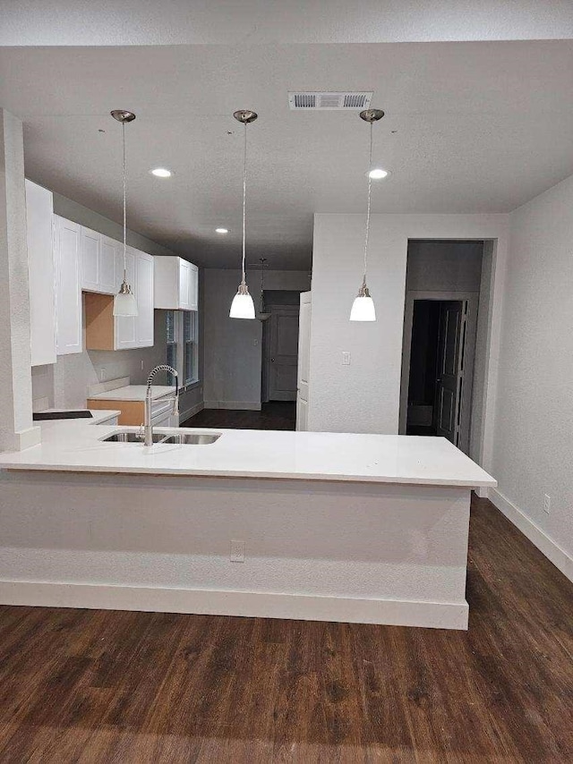 kitchen featuring kitchen peninsula, sink, dark hardwood / wood-style floors, and white cabinetry