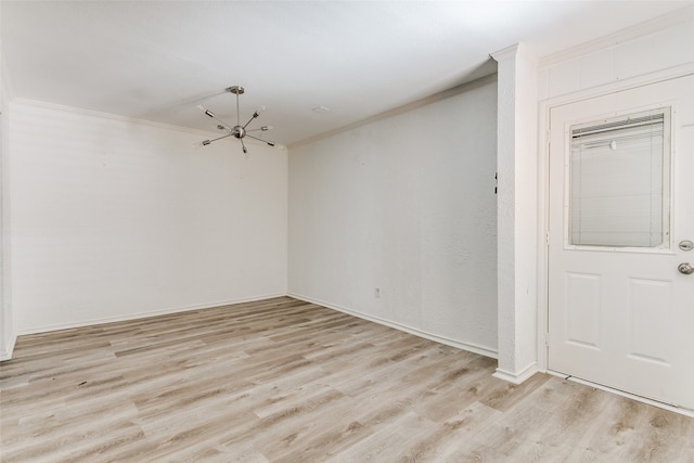 spare room with crown molding, a notable chandelier, and light hardwood / wood-style floors