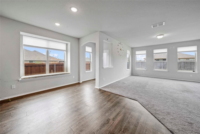 unfurnished living room with a textured ceiling and dark hardwood / wood-style flooring