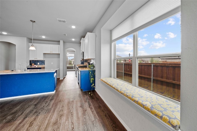 kitchen featuring dark hardwood / wood-style flooring, white cabinetry, backsplash, and plenty of natural light