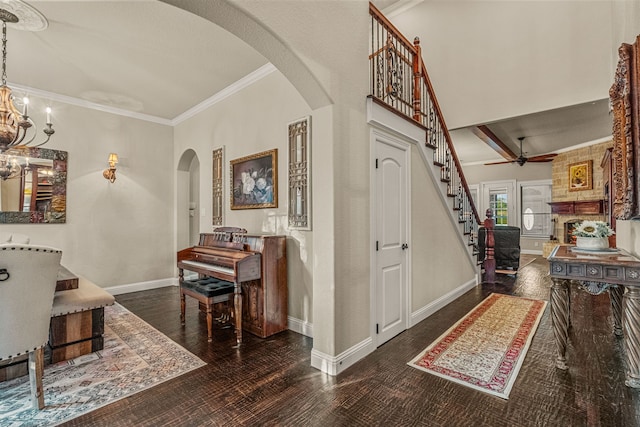 entrance foyer featuring ceiling fan with notable chandelier, dark hardwood / wood-style flooring, ornamental molding, and beamed ceiling