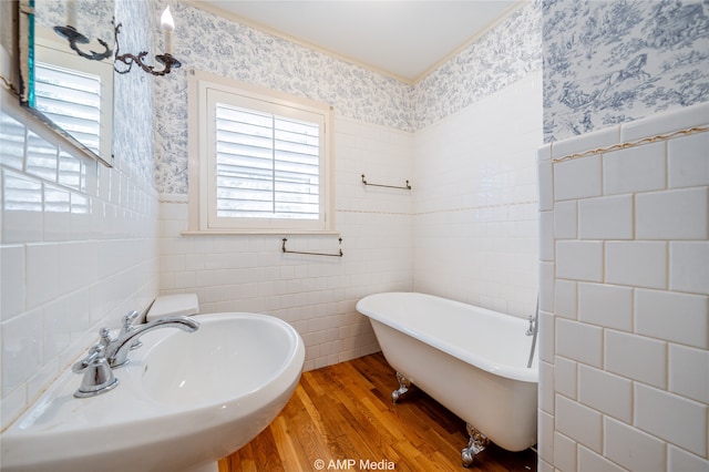 bathroom with tile walls, hardwood / wood-style flooring, a tub, and a wealth of natural light