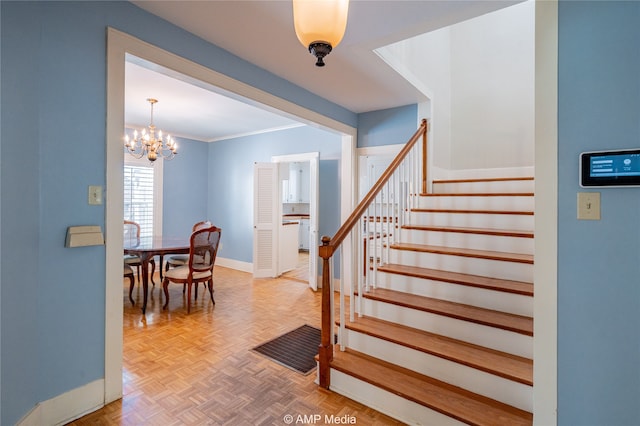 stairs featuring parquet floors, ornamental molding, and an inviting chandelier