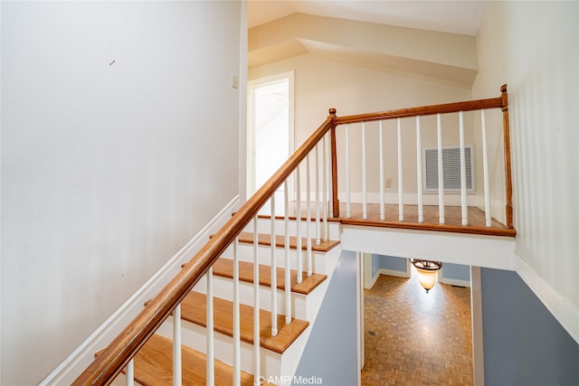 stairway featuring parquet floors and vaulted ceiling