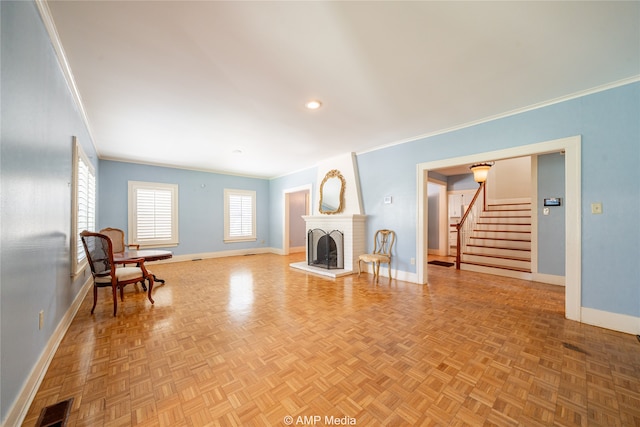 living room with light parquet flooring, crown molding, and a brick fireplace