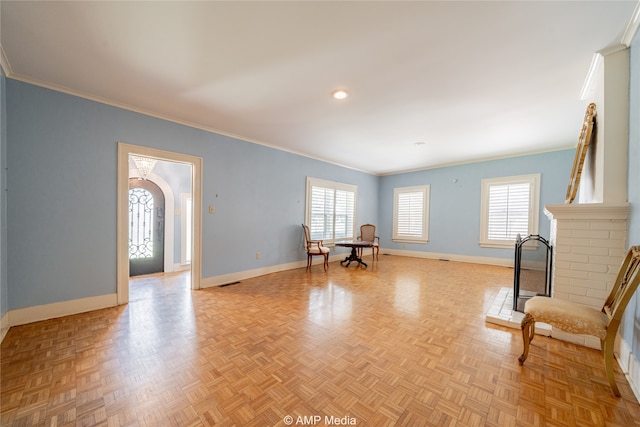 living area featuring light parquet floors, crown molding, and a brick fireplace