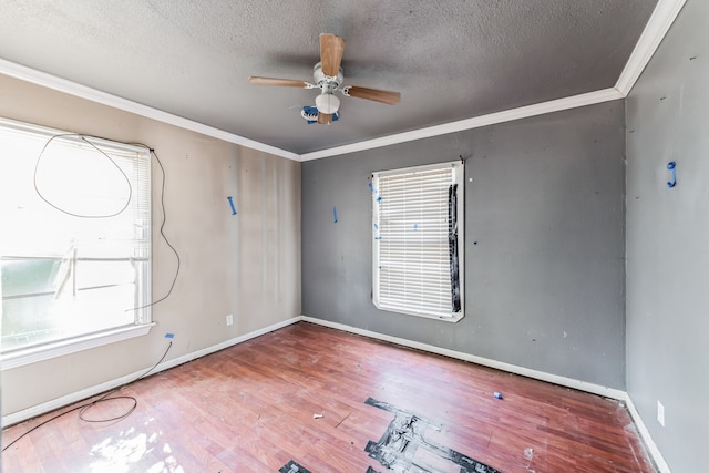 empty room with a textured ceiling, ceiling fan, ornamental molding, and wood-type flooring