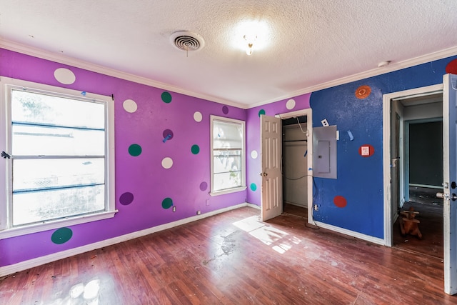 unfurnished bedroom featuring a textured ceiling, a closet, dark wood-type flooring, ornamental molding, and electric panel