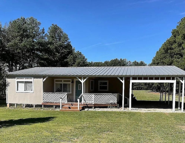 view of front of property featuring covered porch, metal roof, an attached carport, and a front yard