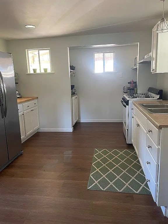 kitchen featuring white cabinetry, decorative light fixtures, dark hardwood / wood-style flooring, sink, and appliances with stainless steel finishes