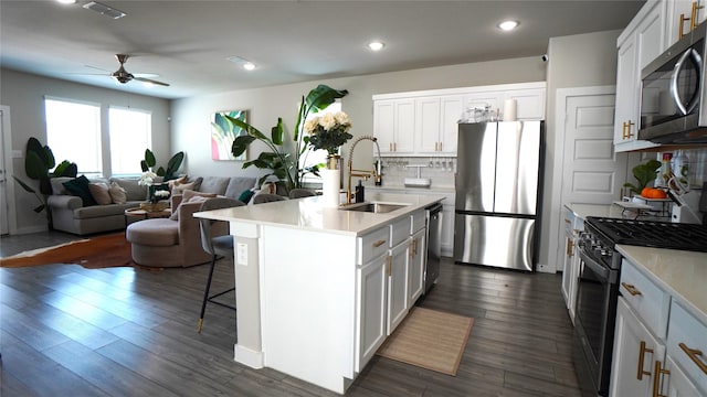 kitchen with dark hardwood / wood-style flooring, appliances with stainless steel finishes, an island with sink, sink, and white cabinetry