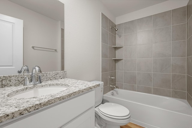 full bathroom featuring hardwood / wood-style flooring, tiled shower / bath, vanity, and toilet