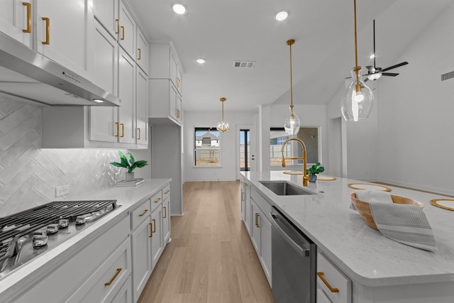 kitchen featuring sink, white cabinetry, appliances with stainless steel finishes, an island with sink, and light stone countertops