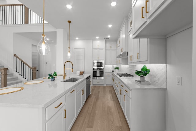 kitchen with sink, decorative light fixtures, stainless steel appliances, and white cabinets