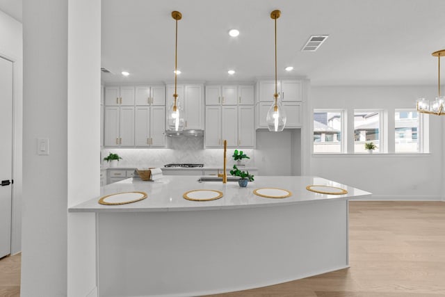 kitchen featuring pendant lighting, backsplash, light hardwood / wood-style floors, and white cabinets