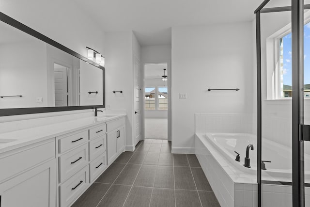 bathroom featuring tile patterned floors, plenty of natural light, vanity, and tiled tub