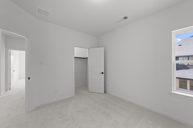 unfurnished bedroom featuring a spacious closet and light colored carpet