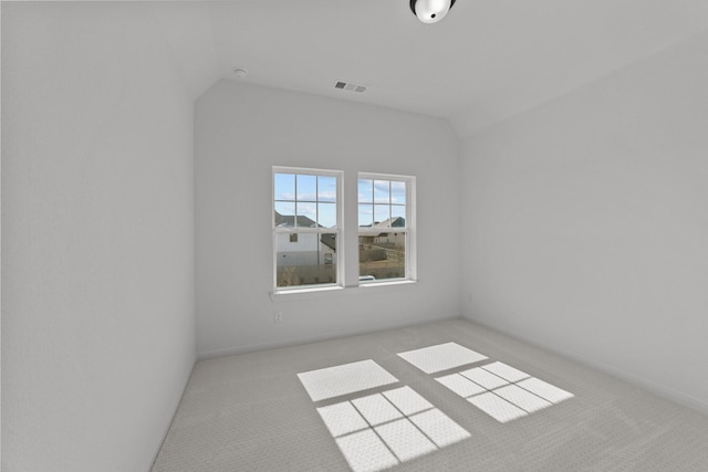 spare room with light carpet and vaulted ceiling