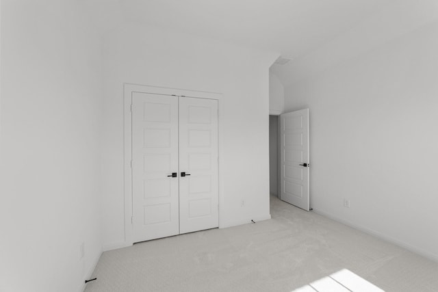 unfurnished bedroom with light colored carpet and a closet