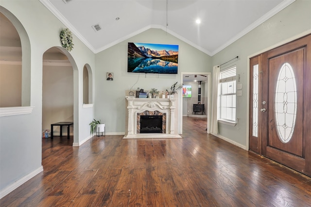 entryway featuring ornamental molding, dark wood-type flooring, vaulted ceiling, and a fireplace