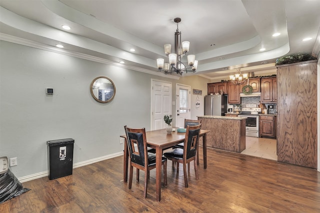 dining room featuring a tray ceiling, dark hardwood / wood-style floors, a chandelier, and ornamental molding