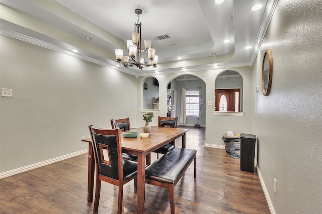 dining space featuring crown molding, a raised ceiling, an inviting chandelier, and dark wood-type flooring