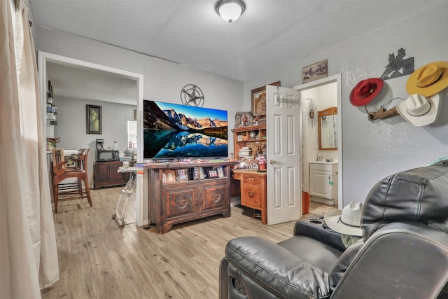 bedroom with ensuite bathroom, light hardwood / wood-style floors, and a textured ceiling