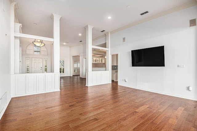 unfurnished living room featuring wood-type flooring and crown molding