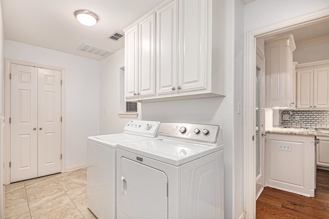 laundry area with cabinets, light wood-type flooring, sink, and washing machine and dryer