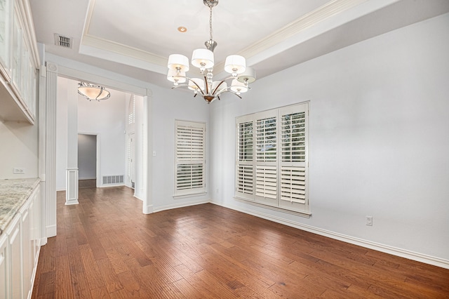 unfurnished dining area featuring ornamental molding, a tray ceiling, dark hardwood / wood-style floors, and a chandelier