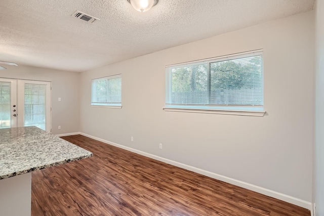 interior space with visible vents, a textured ceiling, french doors, baseboards, and dark wood-style flooring